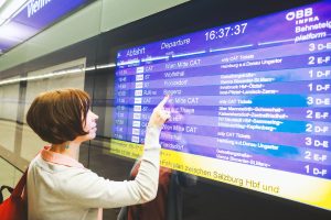 VIENNA, AUSTRIA,18 MAY 2019: Adult woman looking to information monitor with train timetable inside subway station